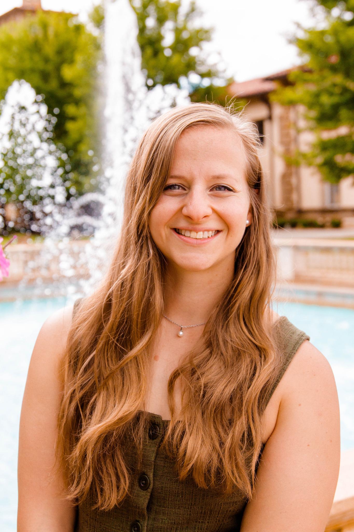 Alyssa smiling outdoors beside a fountain