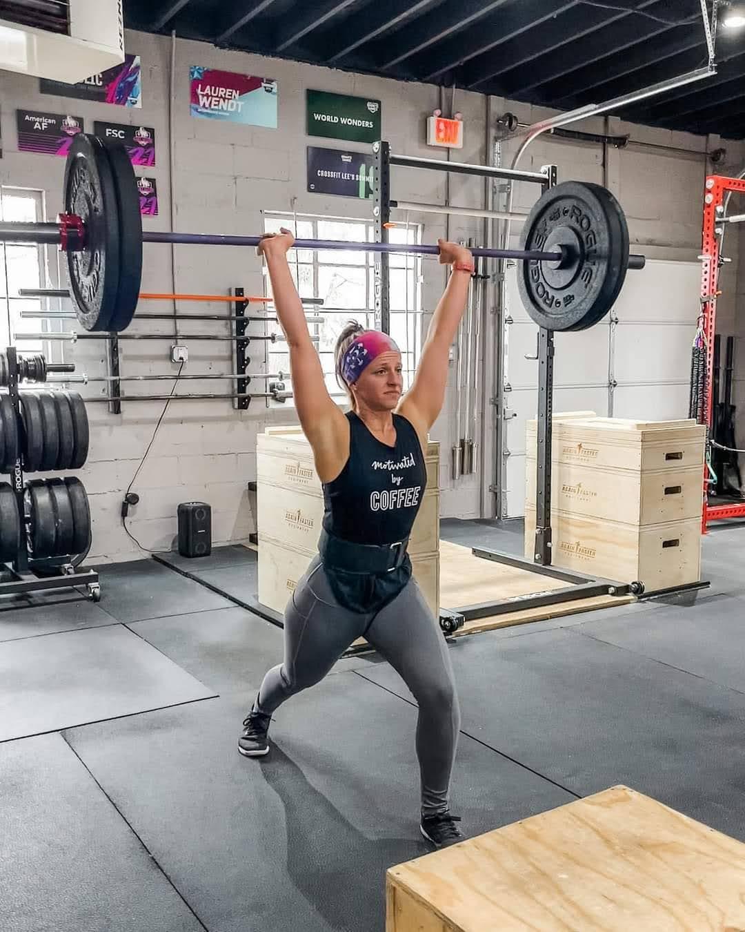 Alyssa lifting a barbell overhead during a workout